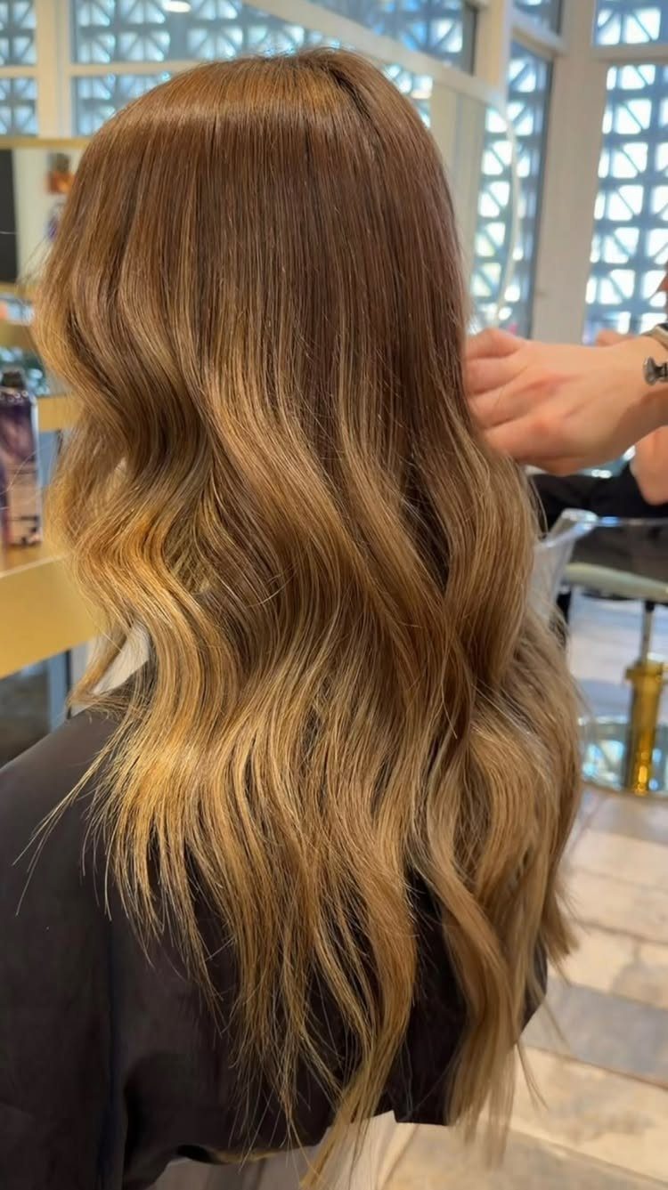 Long wavy dirty blonde hair with darker lowlights and golden ends in a salon