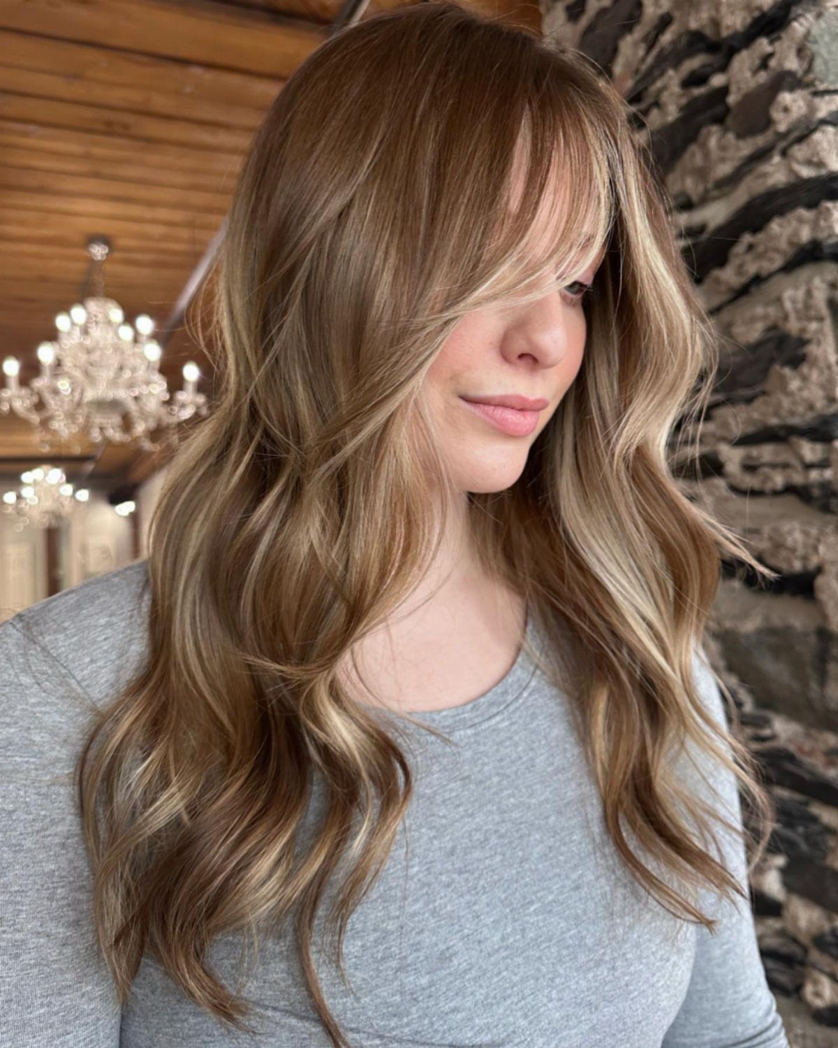 Woman with long, wavy dusty blonde hair and lighter face-framing strands