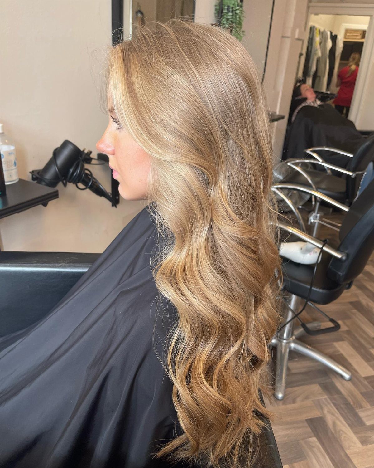 Long wavy honey-blonde hair with fine lighter babylights in a salon