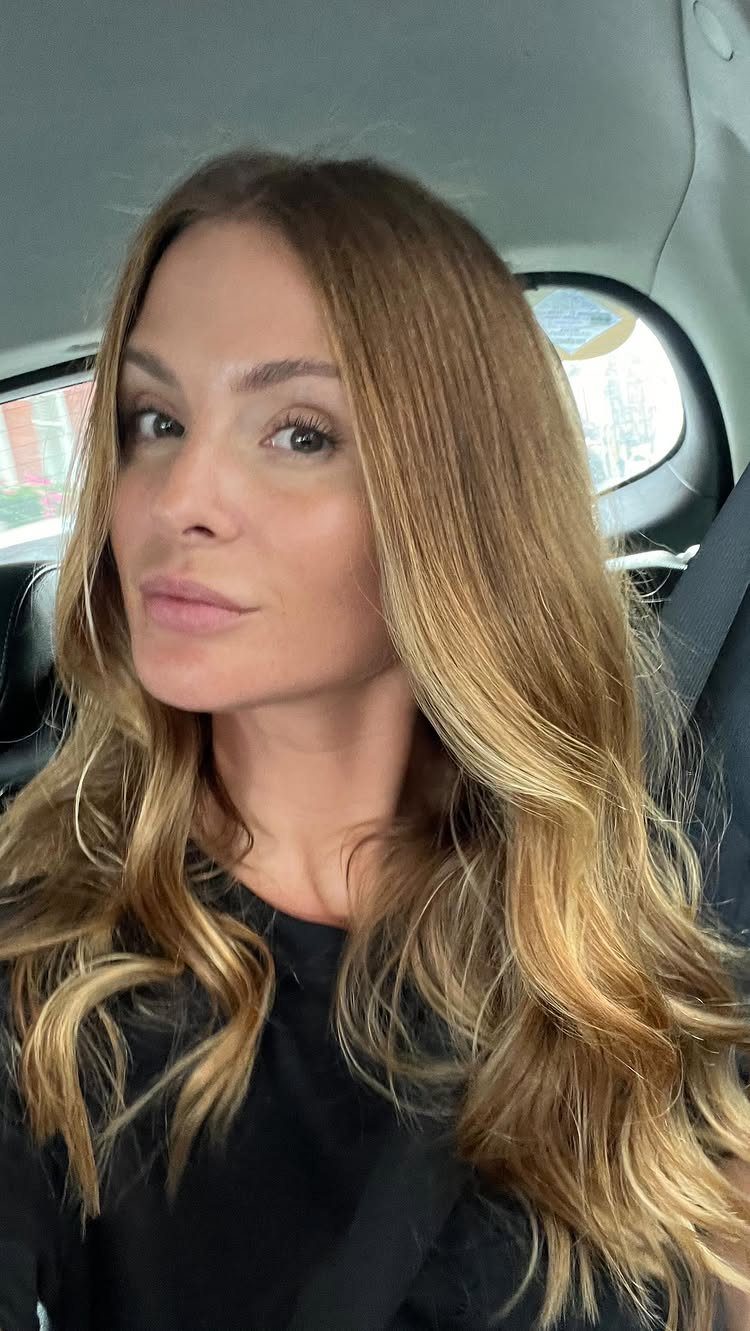 Woman with long, wavy honey-toned dirty blonde hair sitting in a car