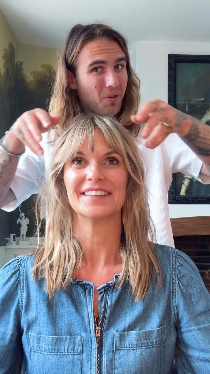 Woman with wavy light dirty blonde hair and bangs in a denim shirt