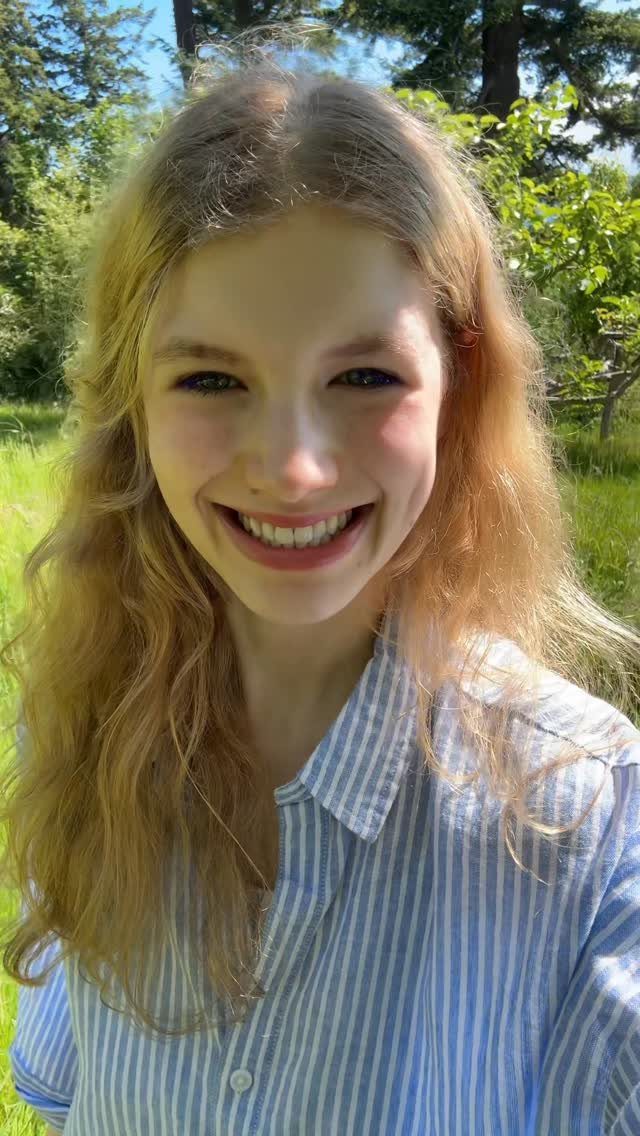 Young woman with long, wavy golden-blonde hair outdoors in sunlight
