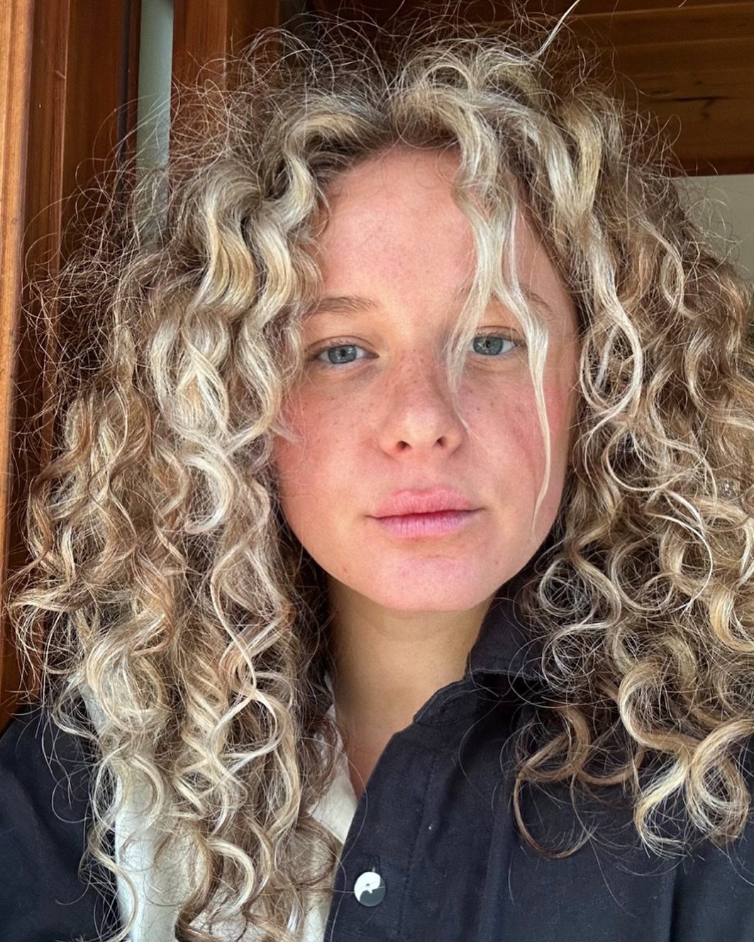 Person with voluminous textured dirty blonde curls and darker roots