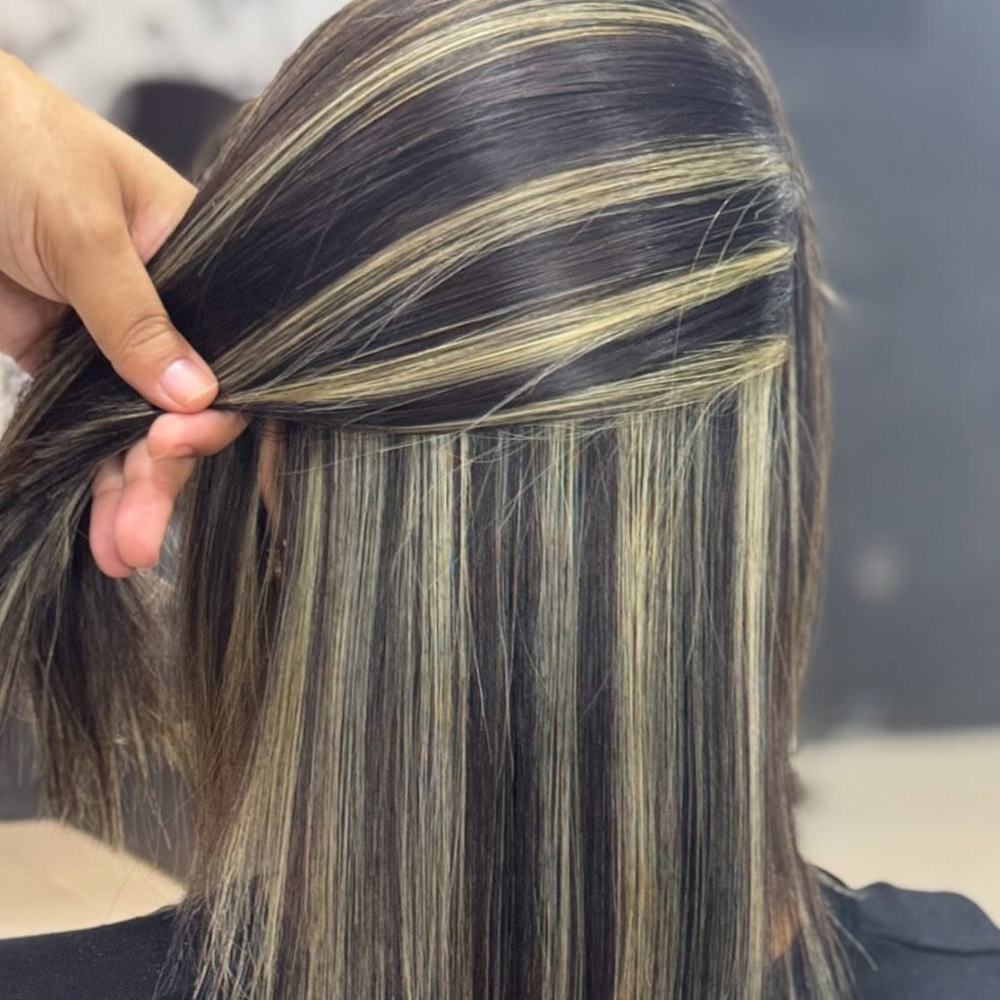 Straight dark hair with fine ash and platinum highlights separated by a hand