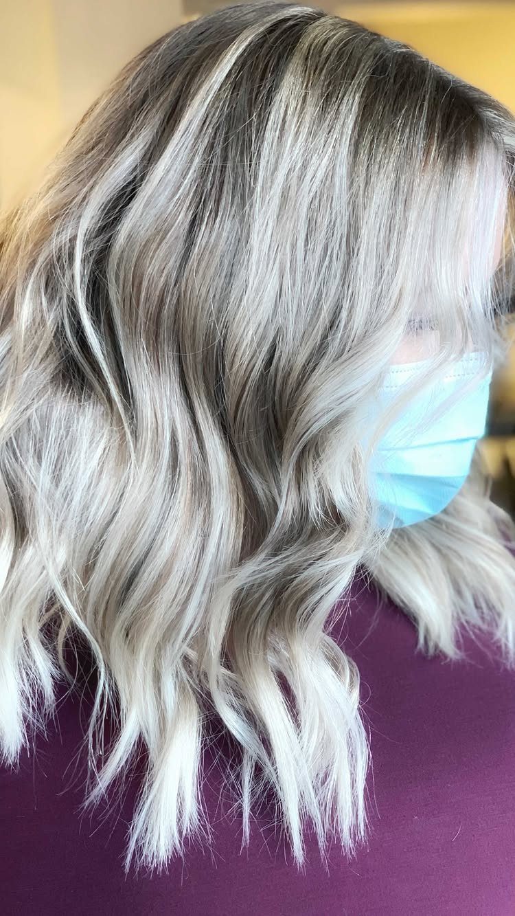 Wavy silver-blonde hair with fine platinum streaks and dark roots
