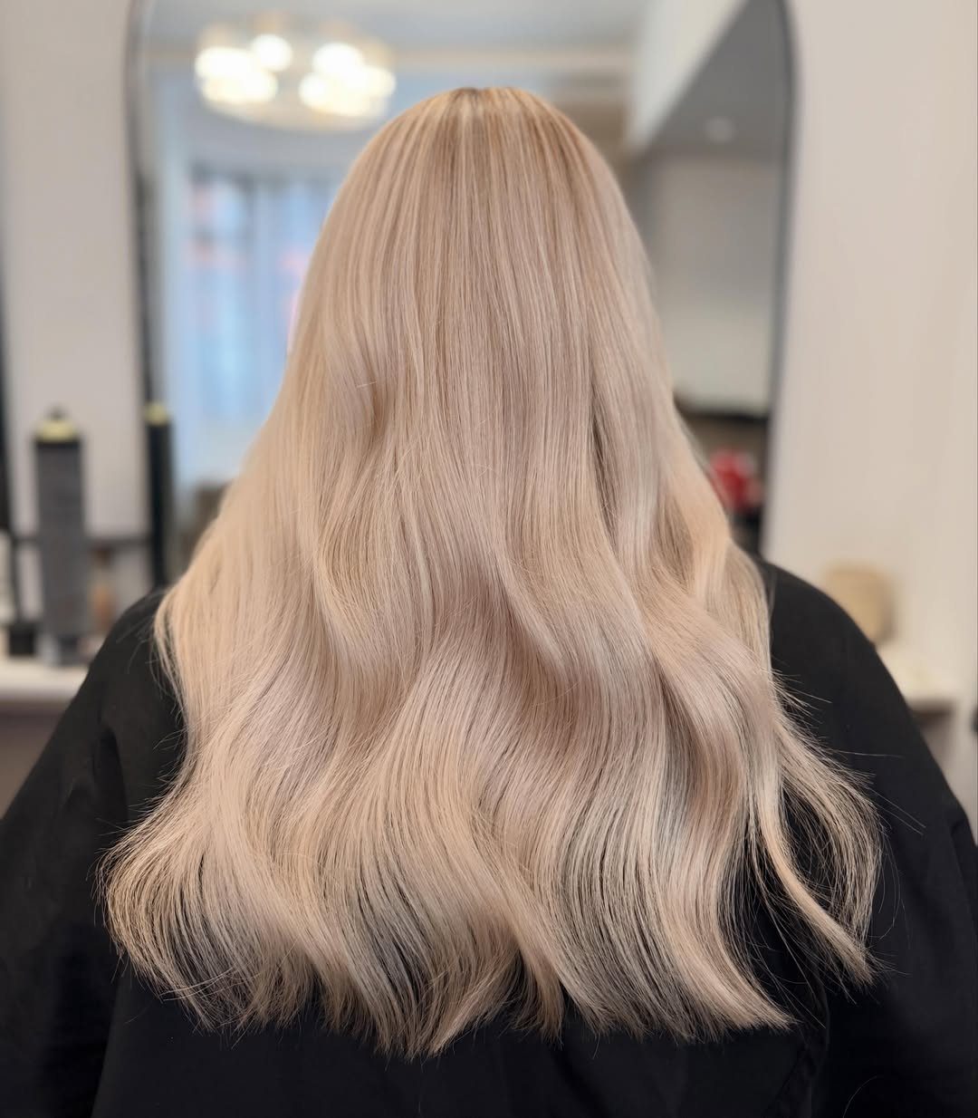 Long pale blonde hair styled in smooth, flowing waves from the back