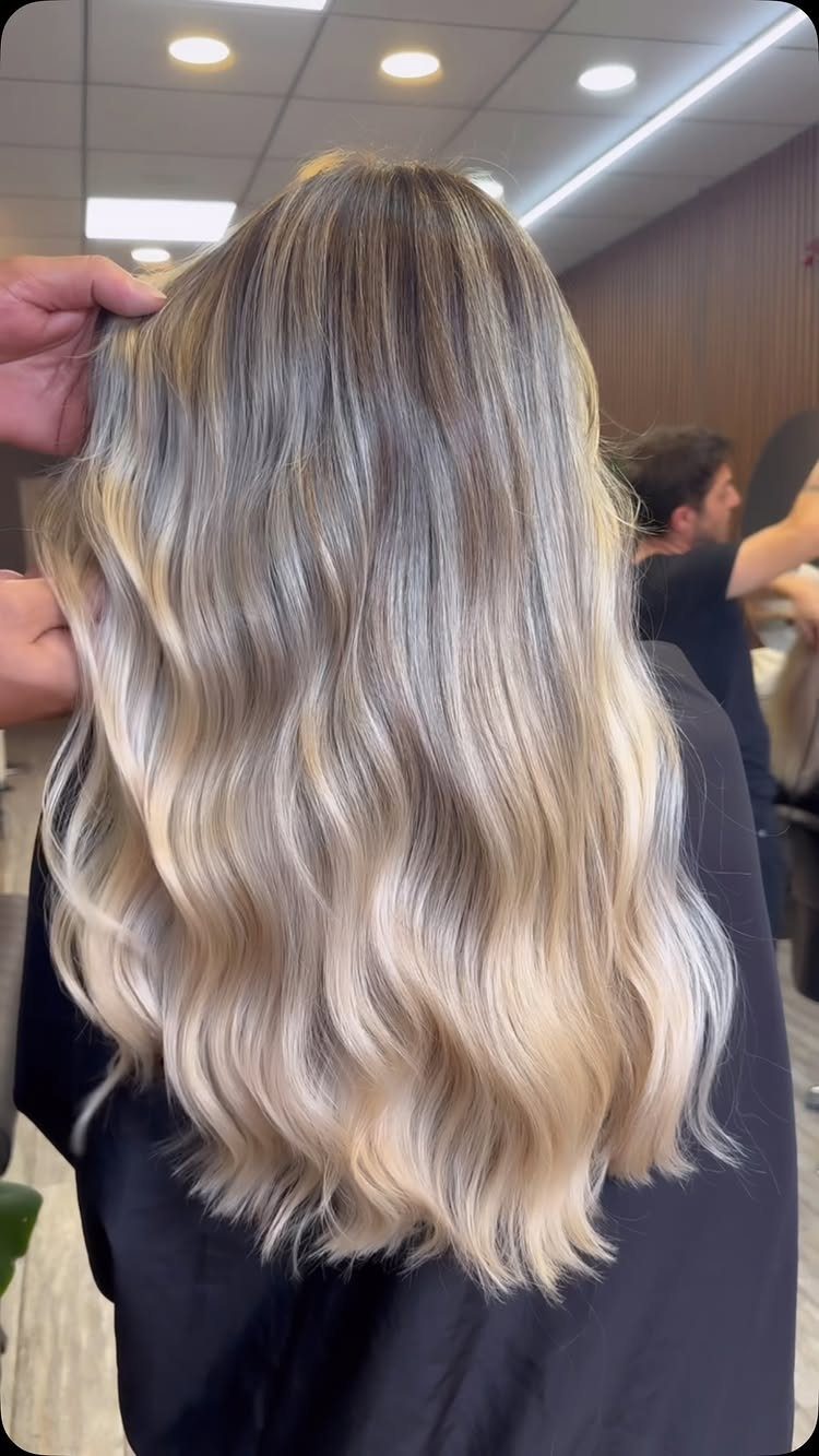 Long wavy beige bronde hair blends into icy blonde pieces over darker roots