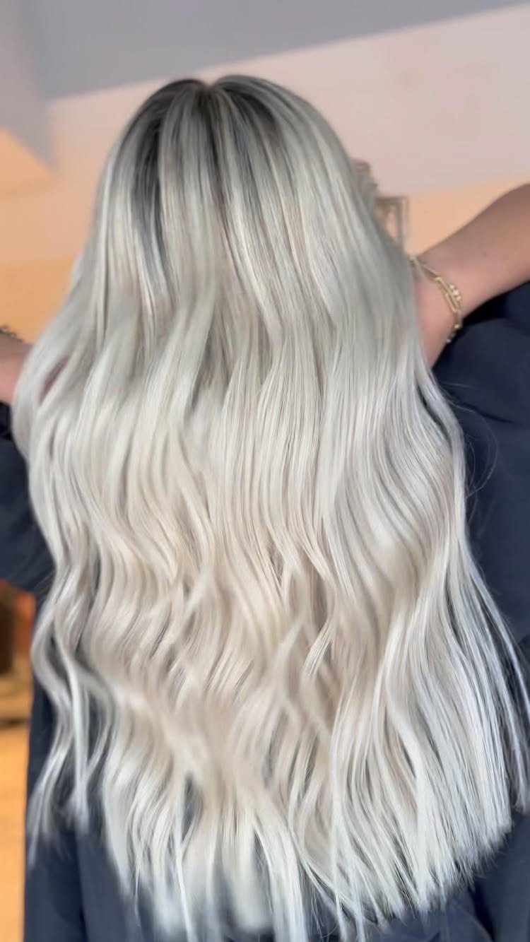 Long creamy platinum blonde hair with dark roots and soft waves