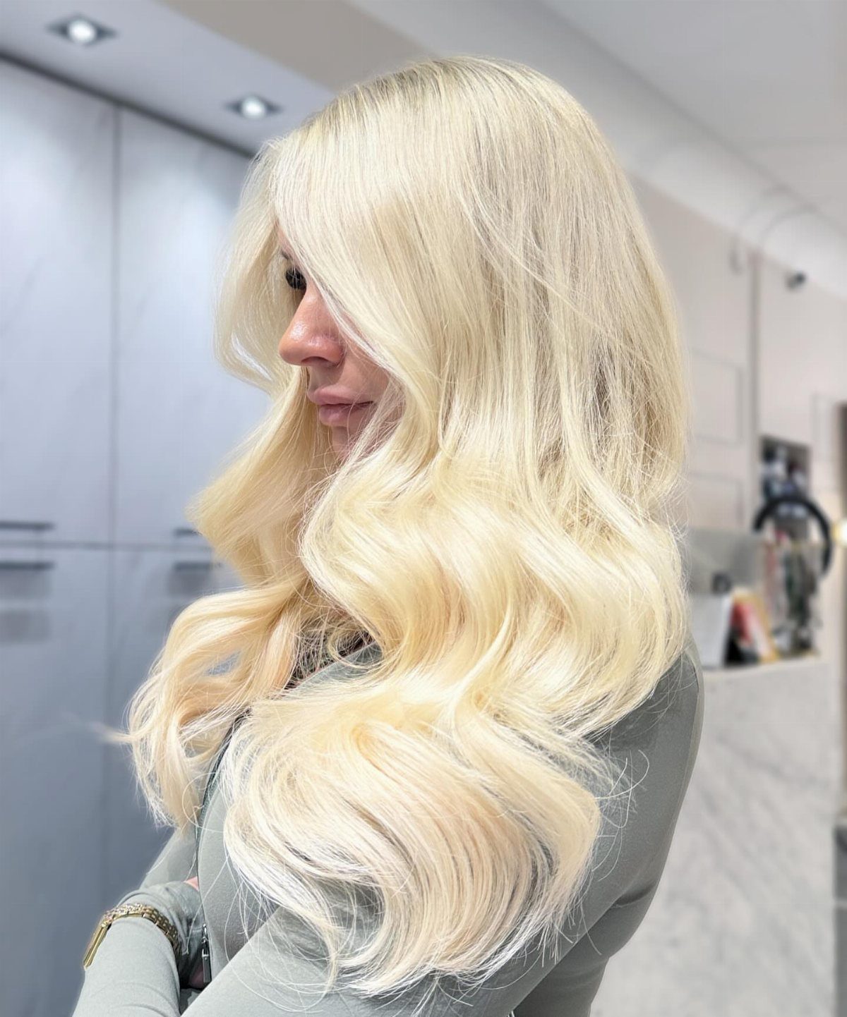 Woman with long, voluminous golden platinum blonde hair styled in loose waves
