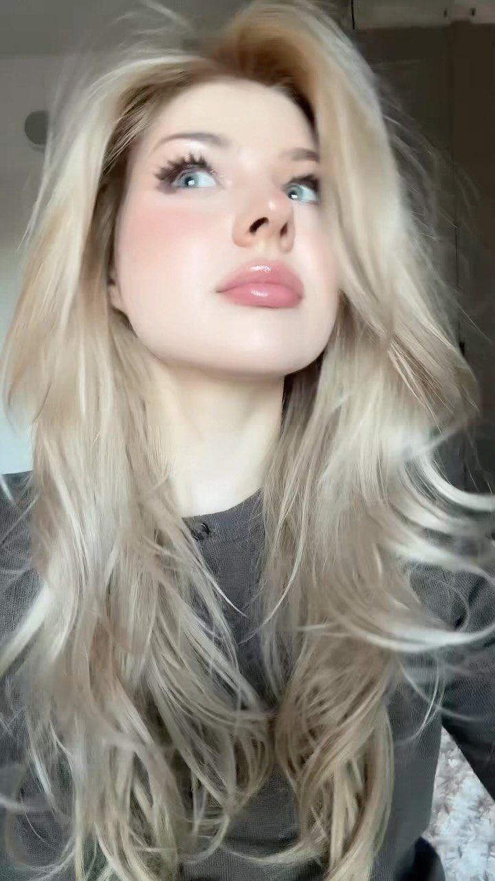 Woman with long, tousled beige blonde waves and voluminous layers