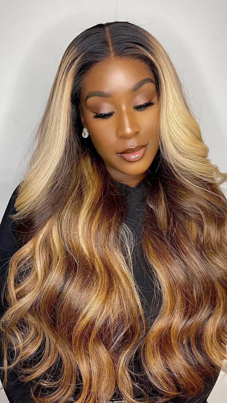 Woman with long wavy hair, dark roots, caramel tones, and broad pale blonde highlights