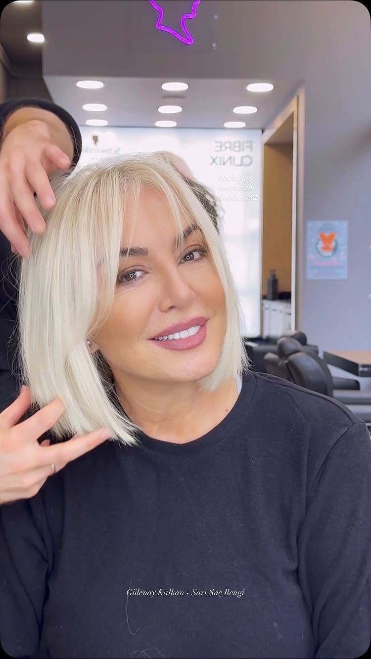 Woman with platinum blonde shoulder-length hair and face-framing bangs in a salon