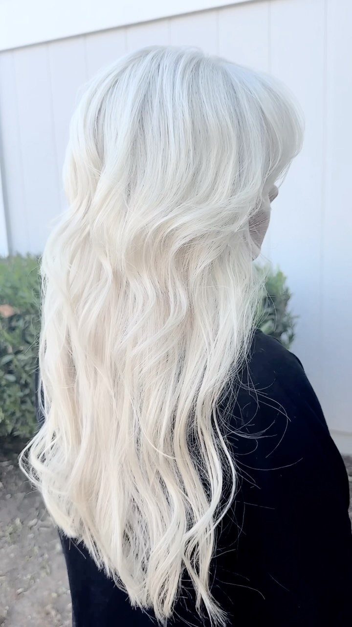Long platinum blonde hair falls in loose waves over a black top