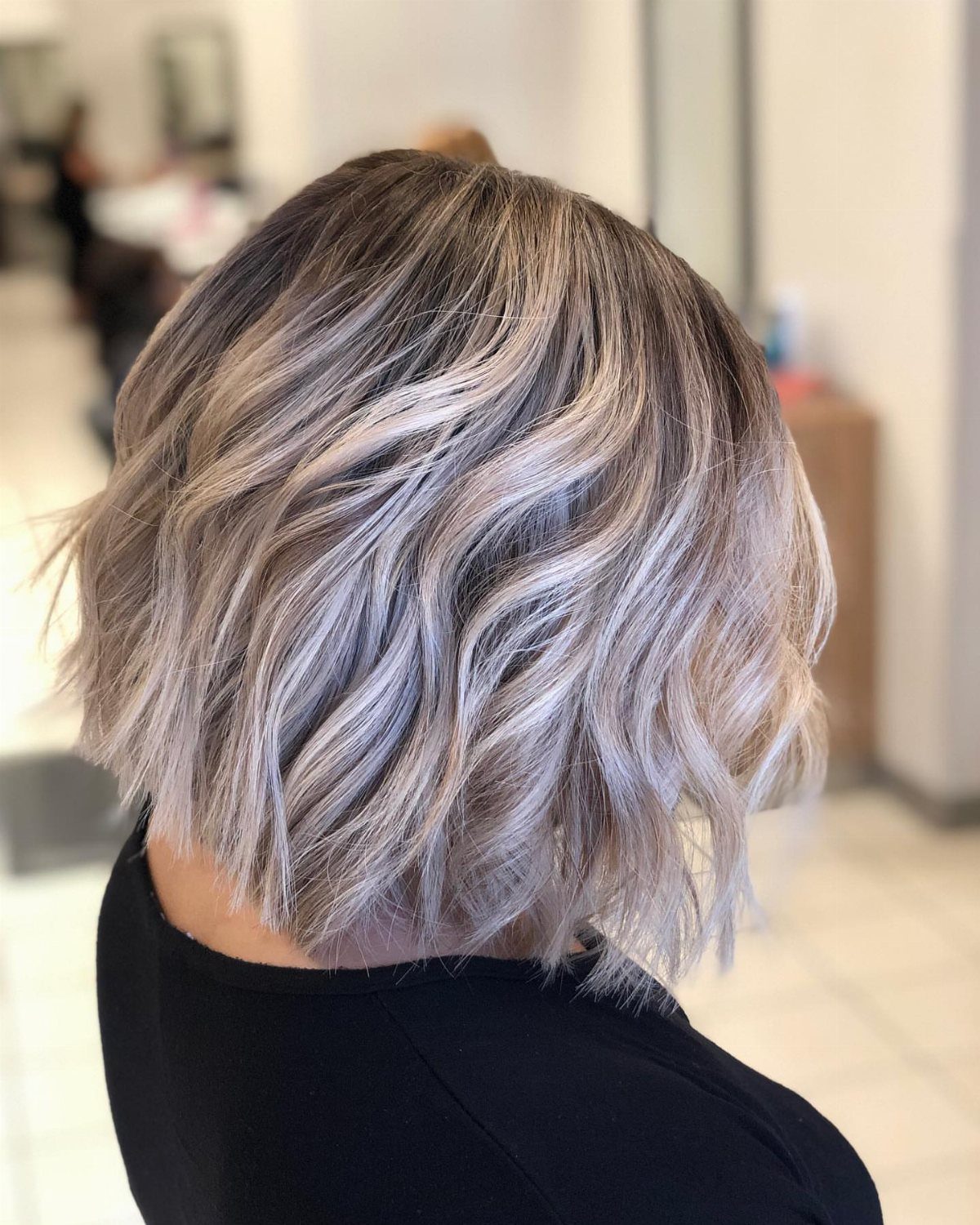 Rooted platinum balayage bob with dark roots and softly waved silver-blonde ends