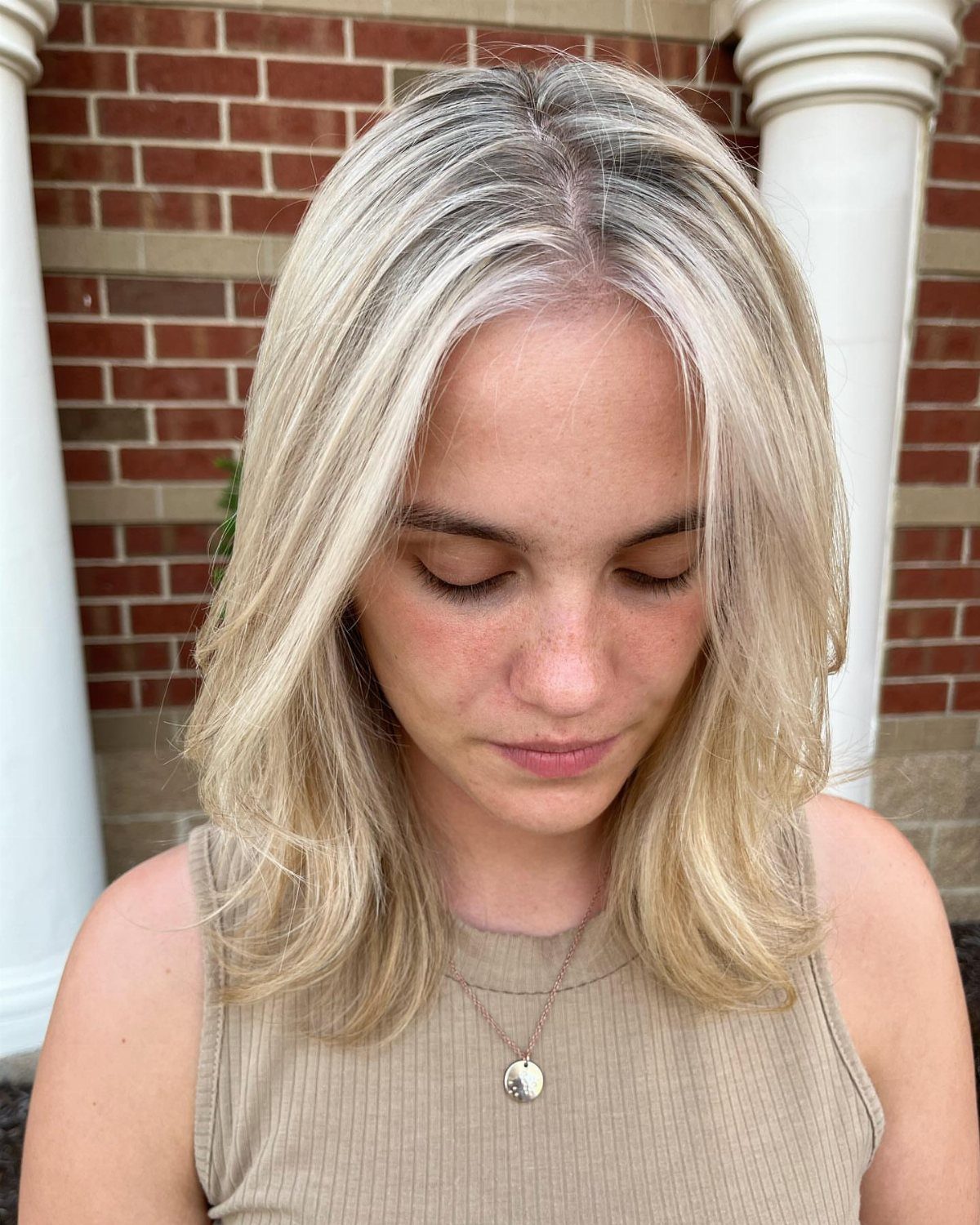 Woman showcasing shoulder-length platinum blonde hair with center part and softly layered ends