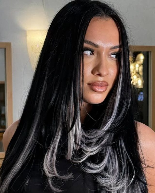 Woman with long black hair and bright platinum face-framing highlights