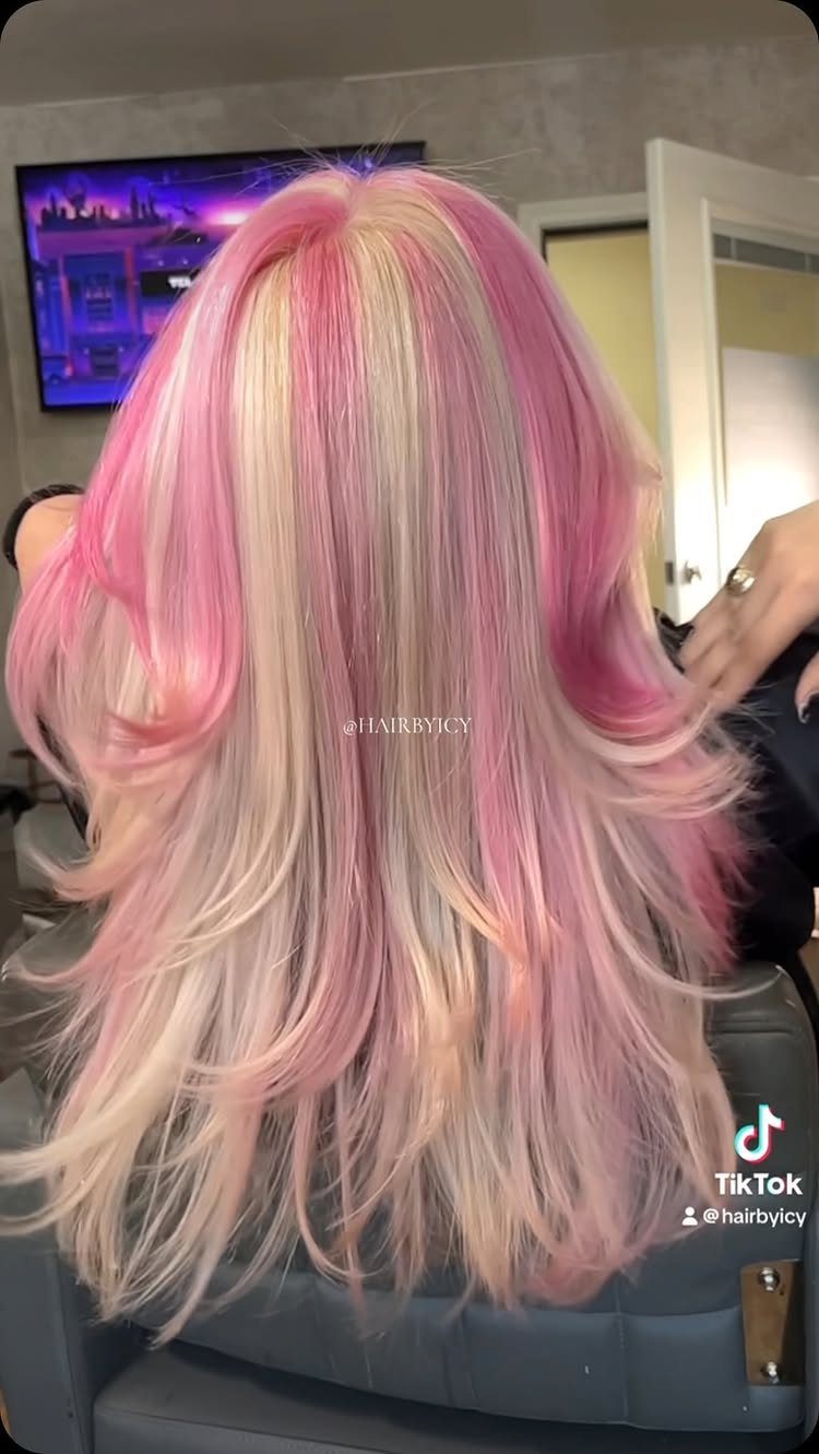 Long layered platinum blonde hair tinted pastel pink in loose curls