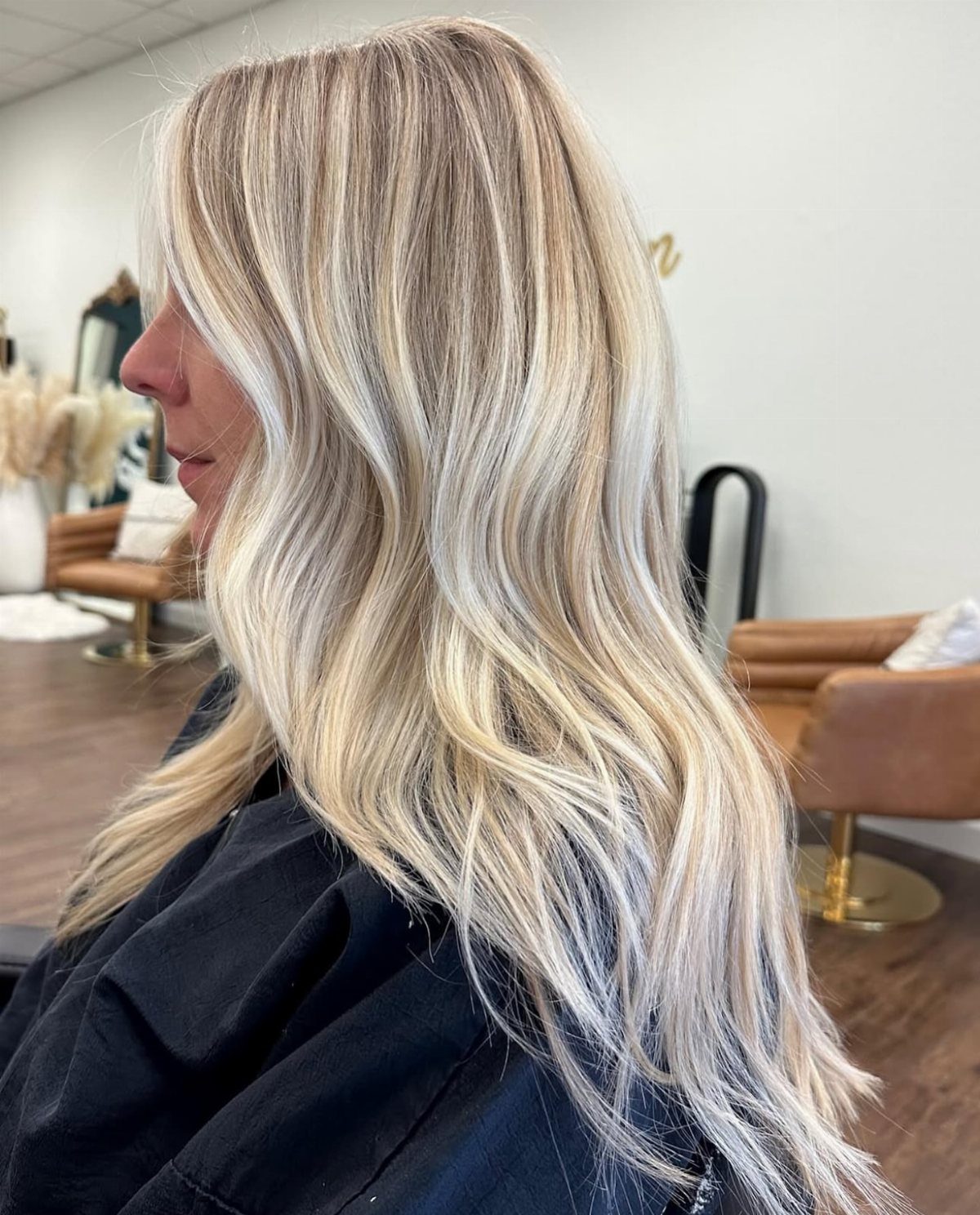 Long wavy sand blonde hair shown on a woman in a salon