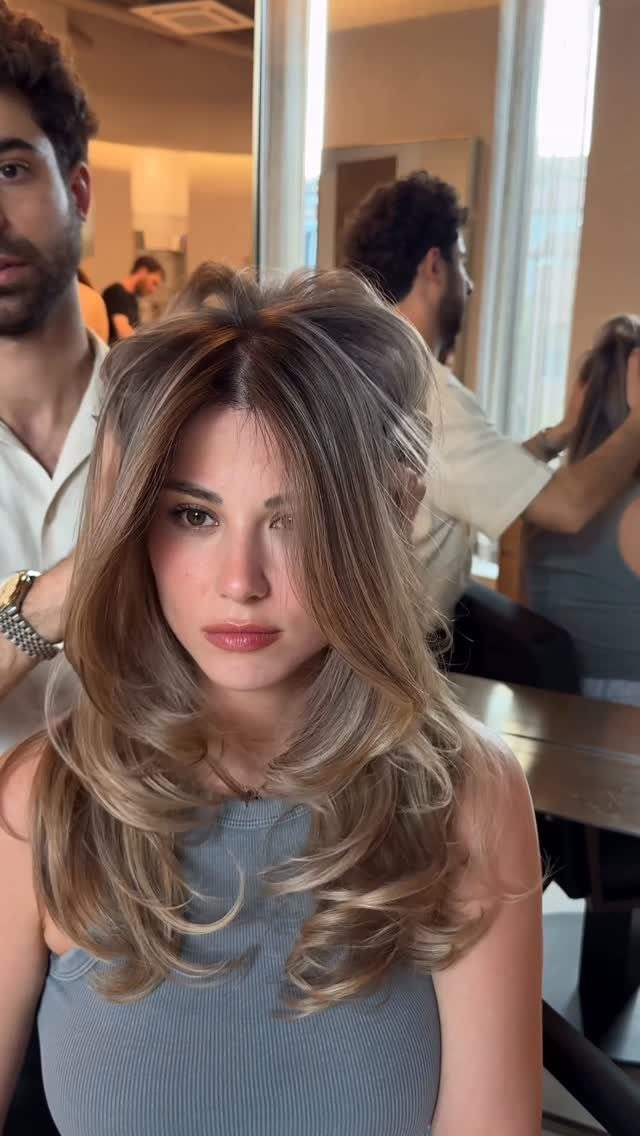 Woman showing layered brown hair with sandy blonde highlights in a salon