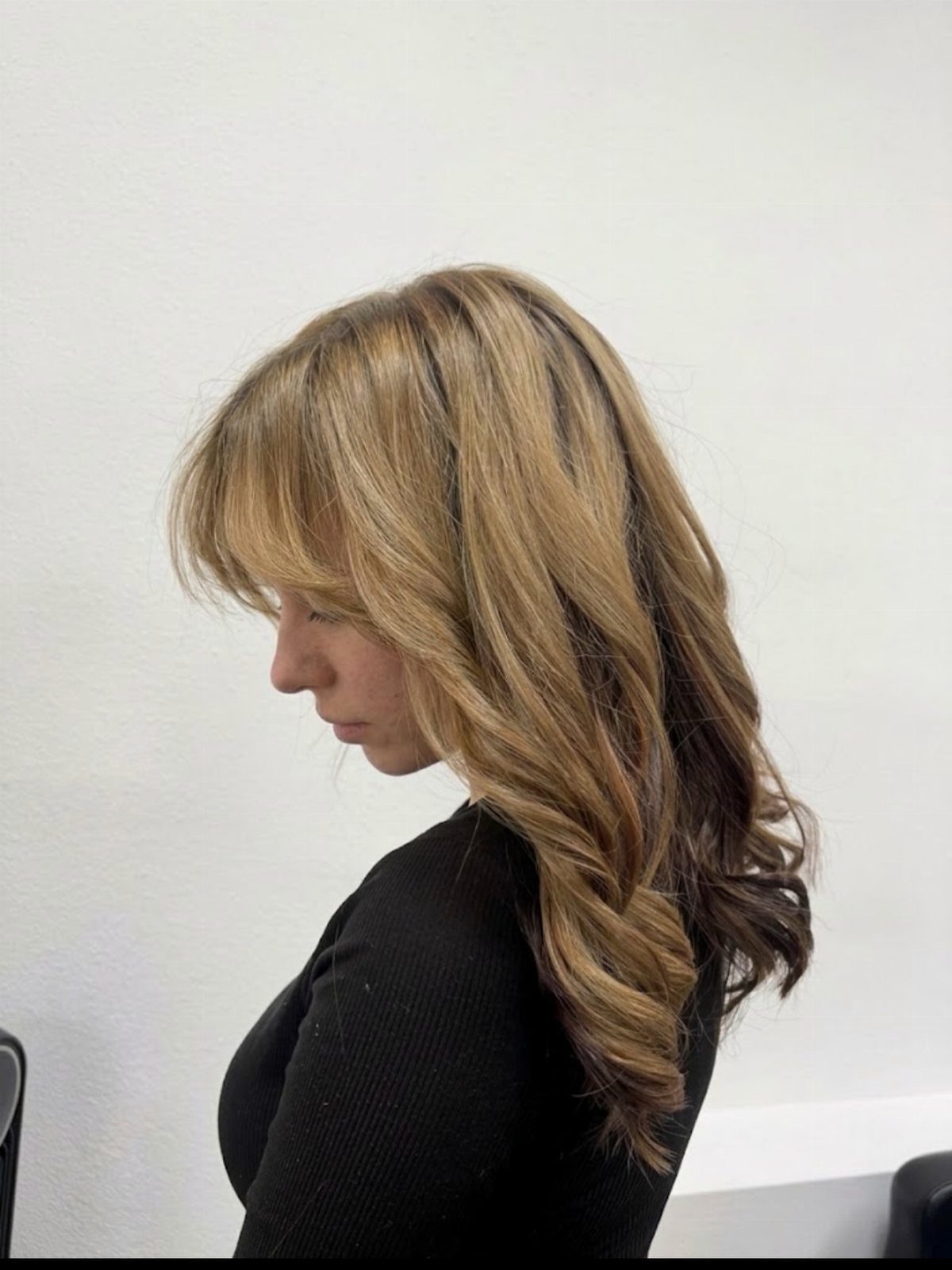 Woman with long sand-blonde layered hair and loose curls in profile