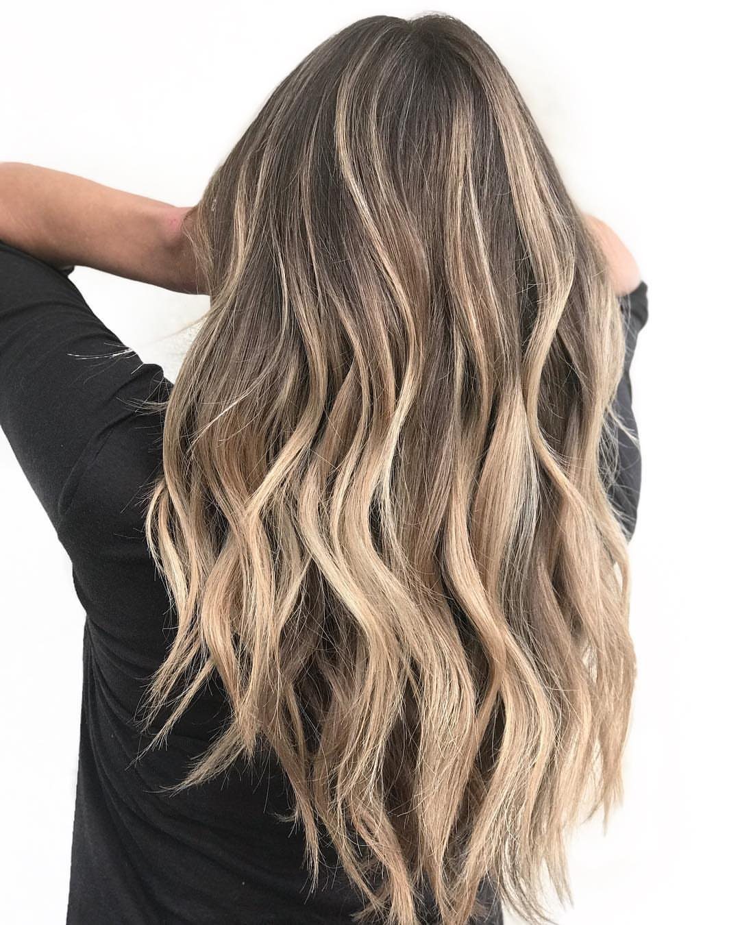 Long wavy sandy blonde balayage hair with dark roots and lighter ends