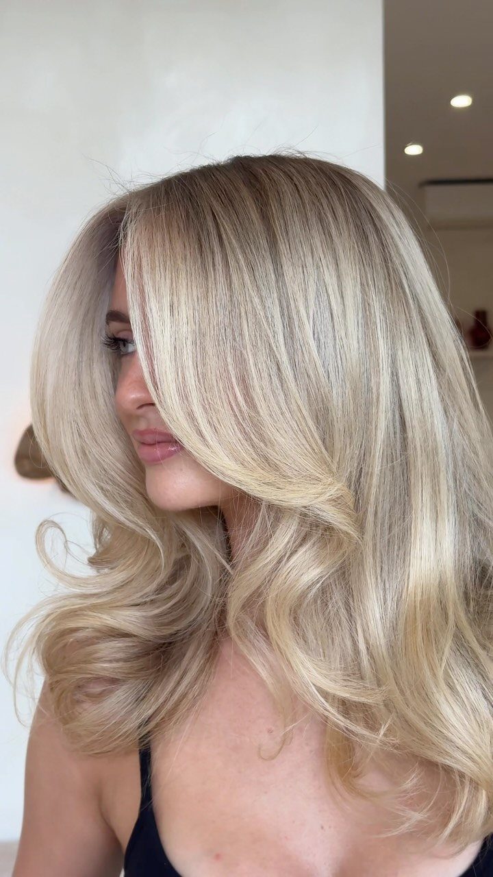 Woman with curled sandy blonde hair and bright face-framing strands