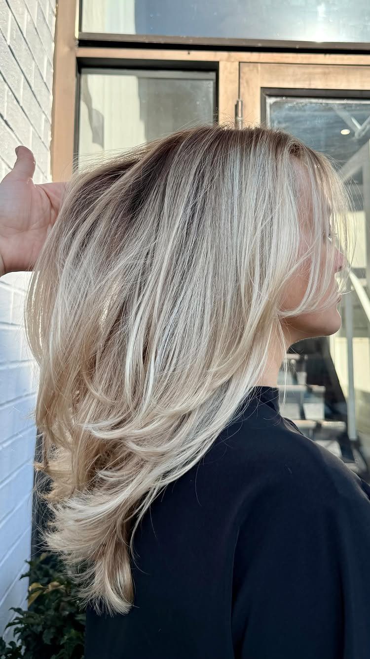 Layered sandy blonde hair with darker roots and pale, feathered lengths