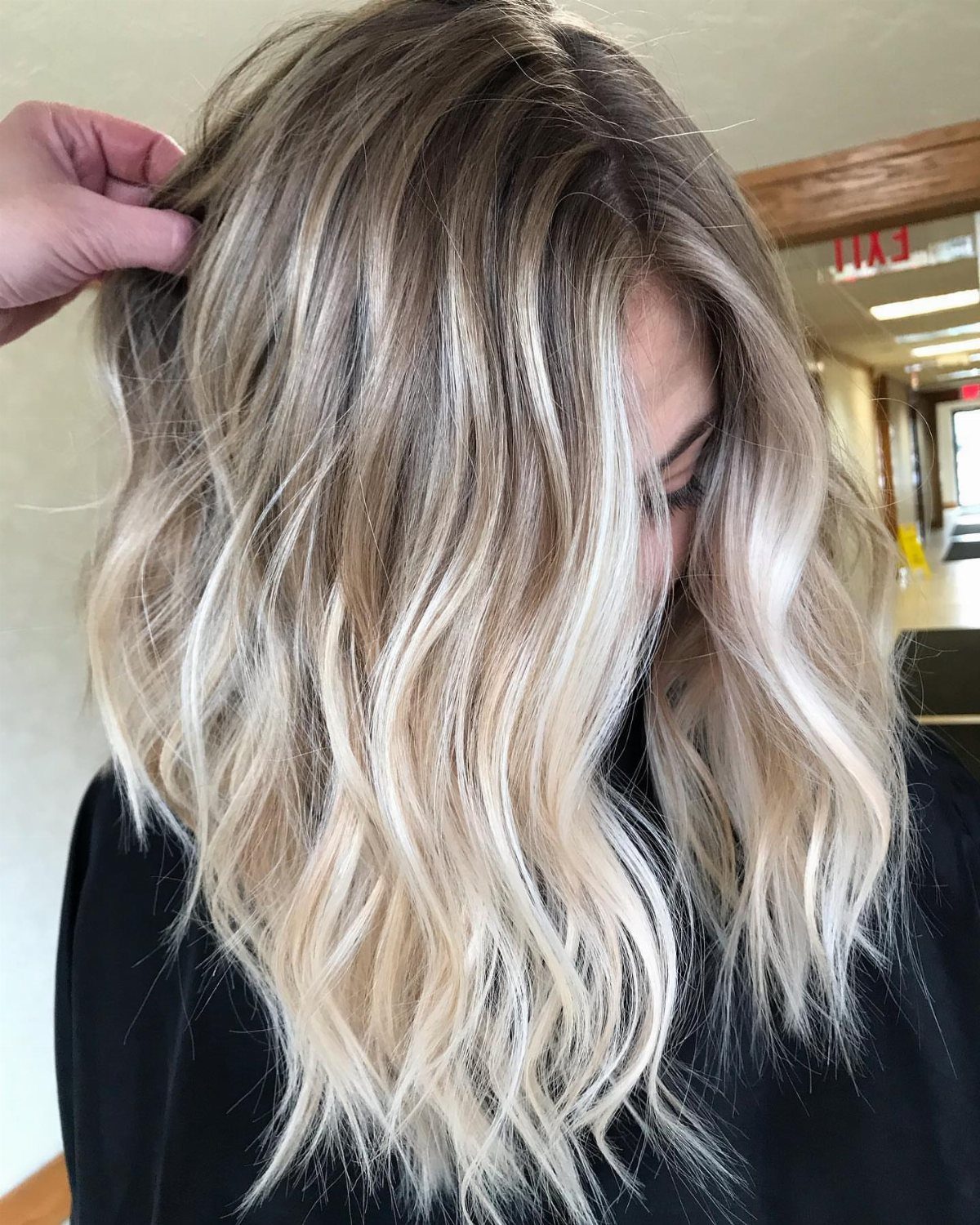 Wavy sandy blonde hair with dark roots blending into lighter lengths