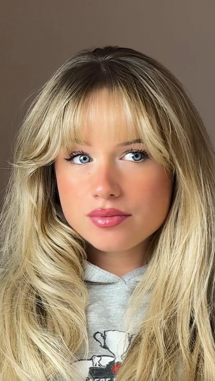 Woman with long sandy blonde waves and wispy curtain fringe