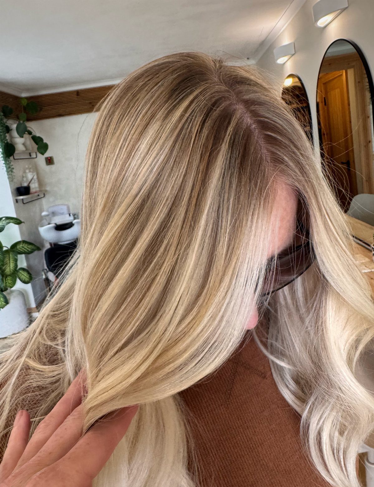 Blended sandy blonde waves show soft golden brightness in a salon