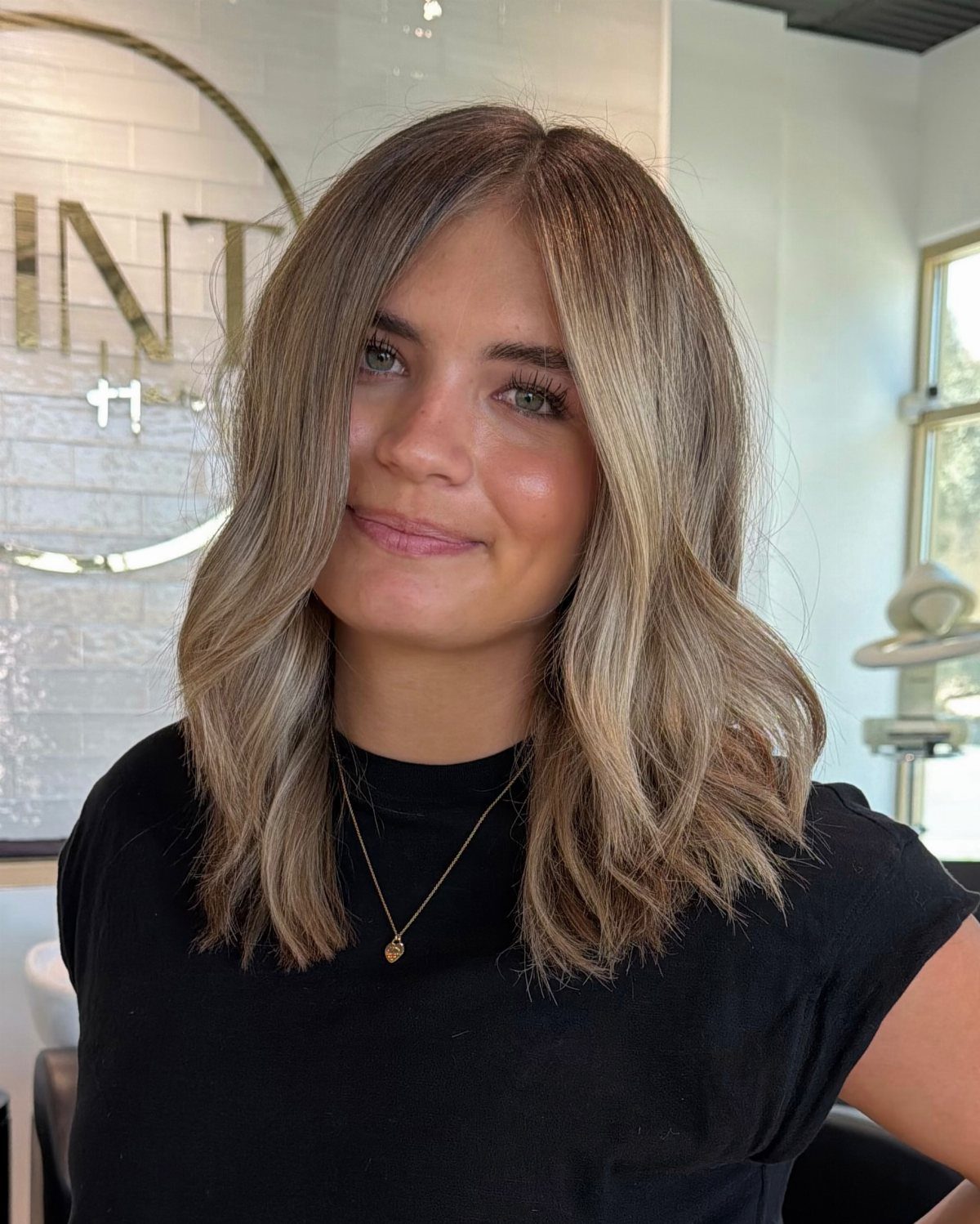 Woman with shoulder-length sandy blonde waves and subtle darker lowlights