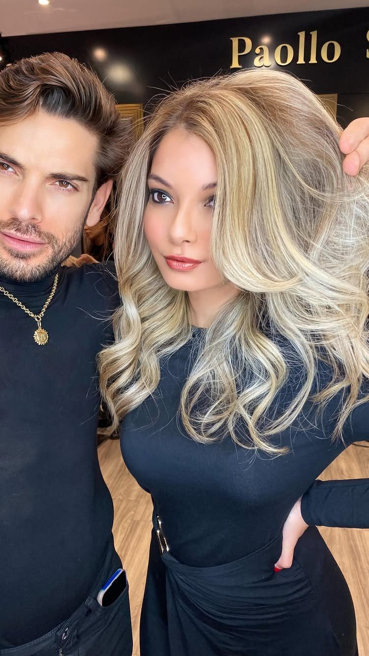 Woman with long, dimensional sandy blonde curls posing beside a man