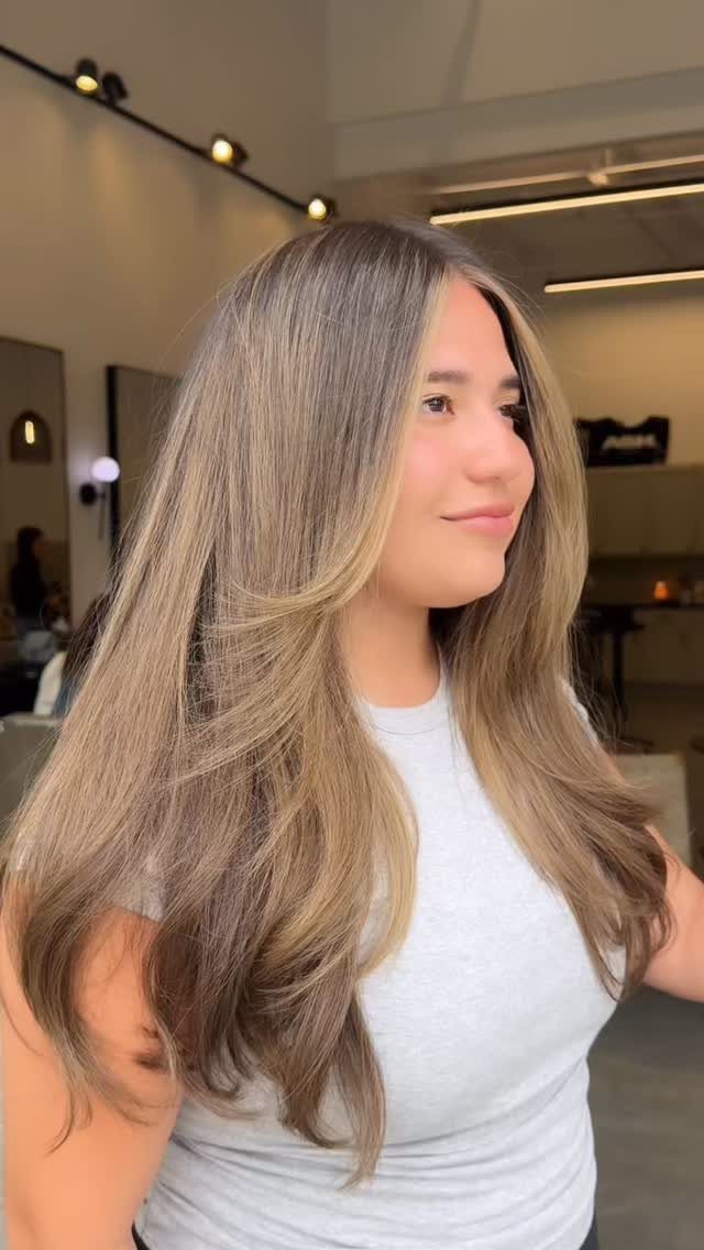 Woman with long, layered sandy blonde hair and subtle lighter strands