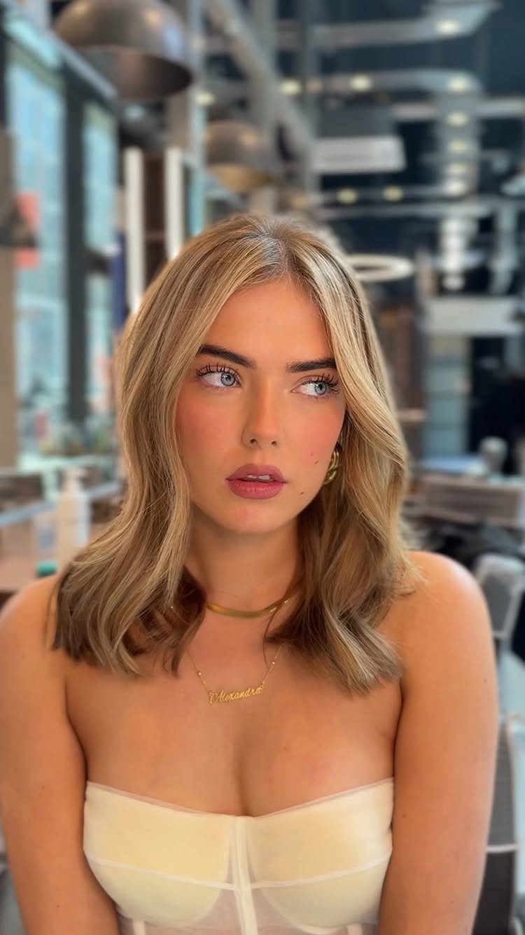 Woman displaying pale sandy blonde layered hair in a bright salon