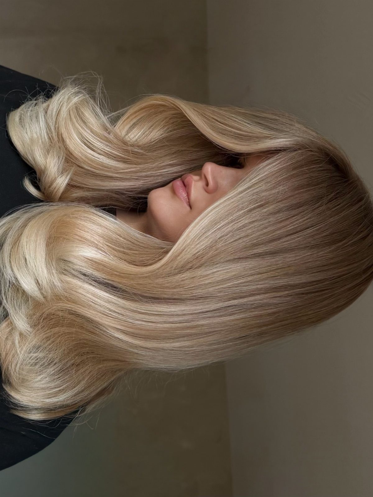 Long beige-blonde hair falls in soft, voluminous waves around a woman's face