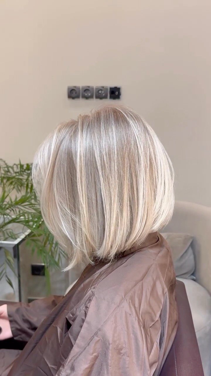Highlighted blonde bob with pale ribbons and darker strands in a salon