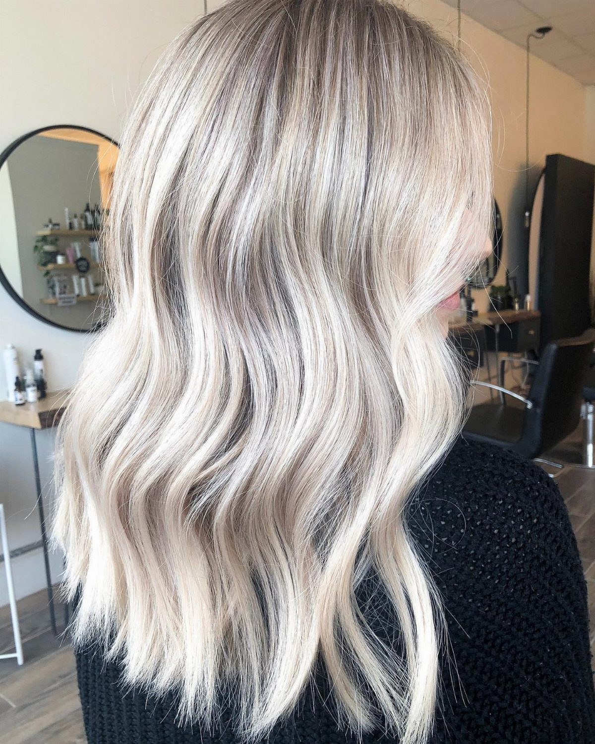 Wavy sandy blonde hair with a soft darker shadow root in a salon