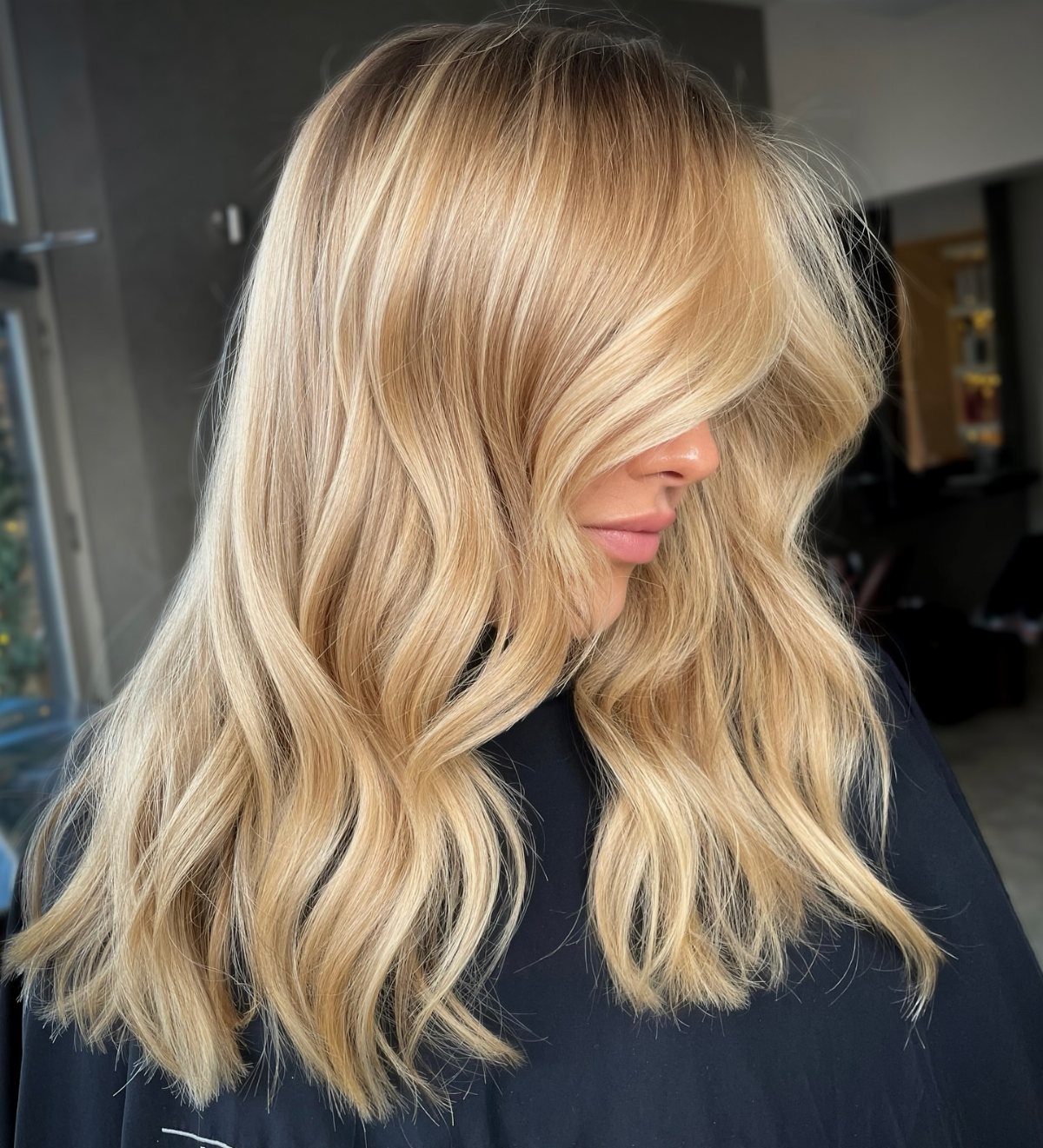 Wavy sandy blonde hair with warm scattered highlights and darker roots