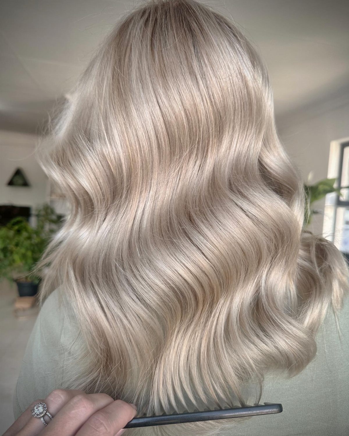 Long pale beige-blonde waves styled with a comb in a salon