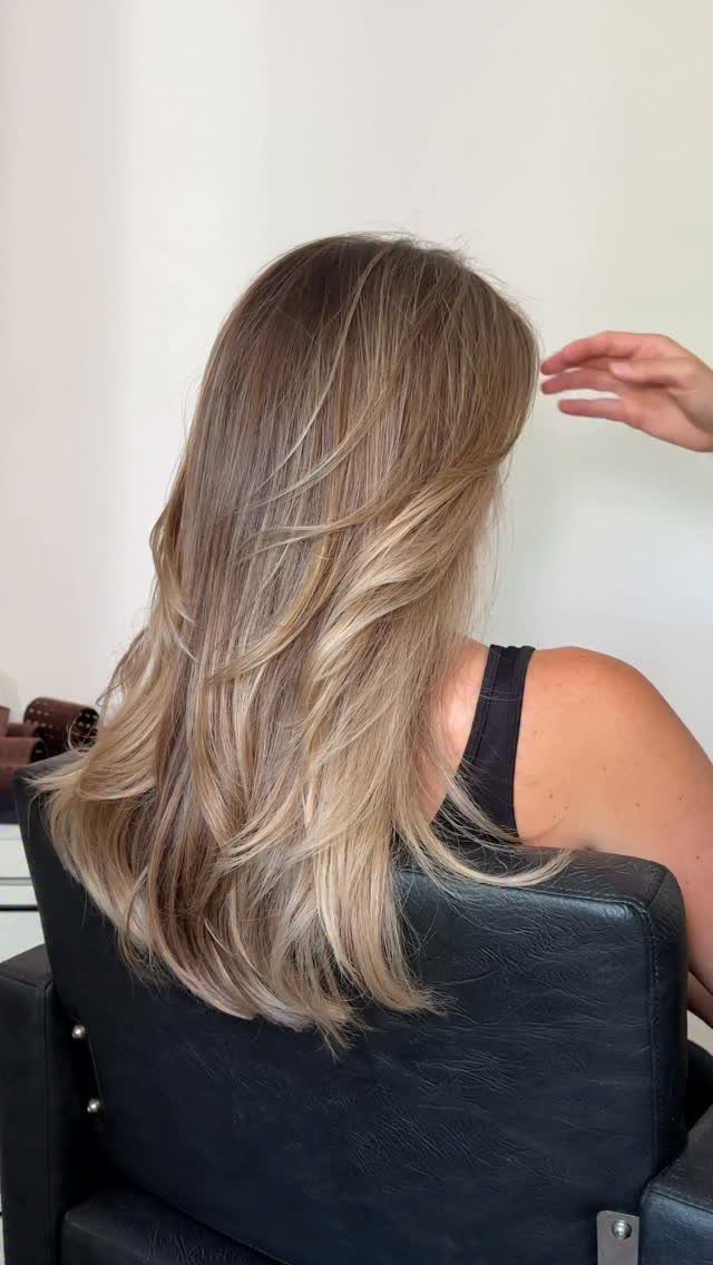 Long layered chestnut blonde hair with cool blonde highlights, seen from behind