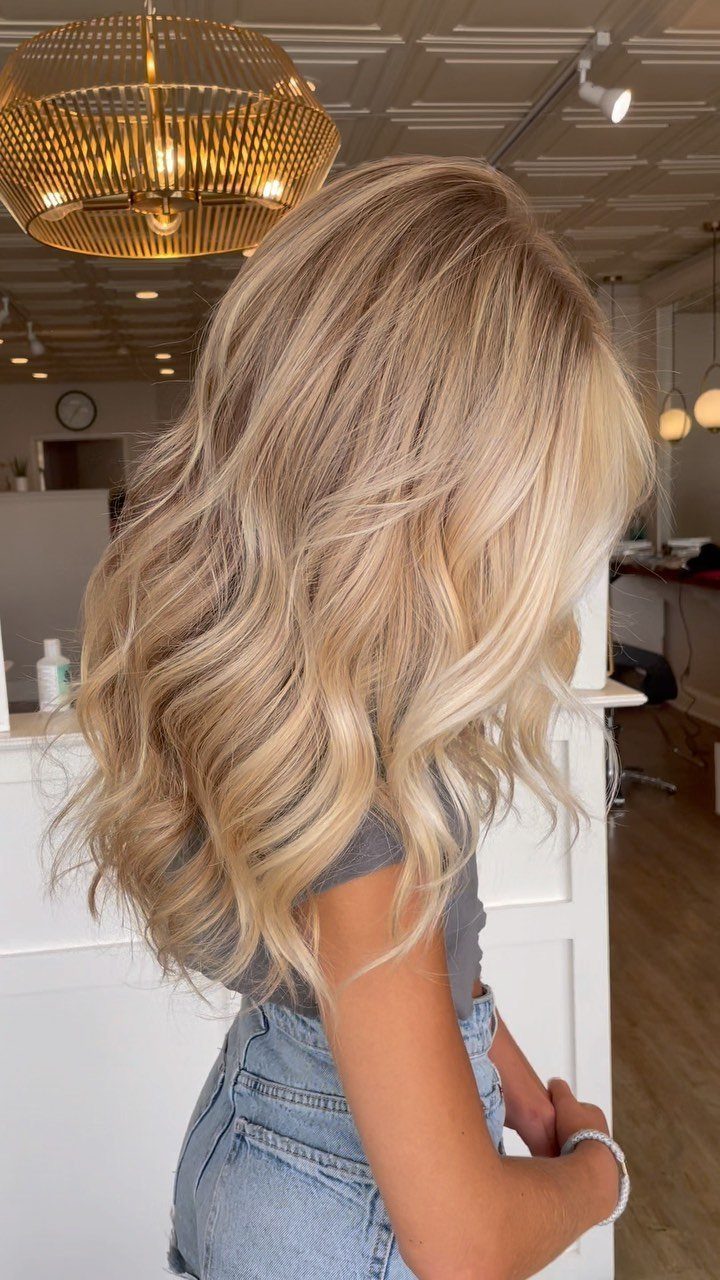 Wavy dirty blonde hair blends darker roots with warm caramel and beige tones