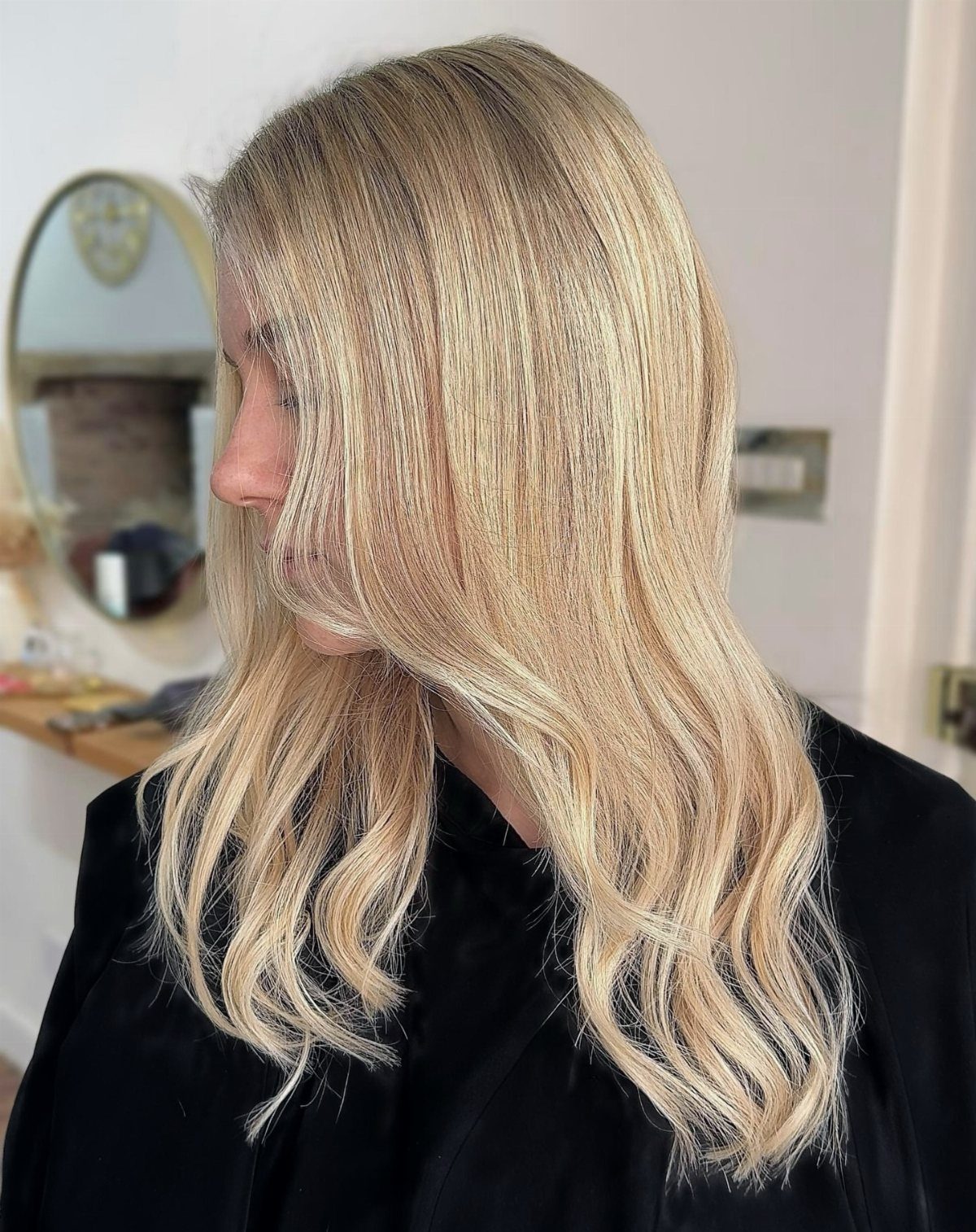 Woman with long wavy golden platinum blonde hair and darker roots