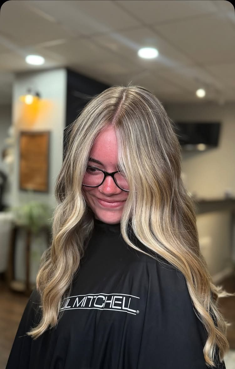 Woman displaying long wavy sandy blonde hair with beige, gold, and light brown tones