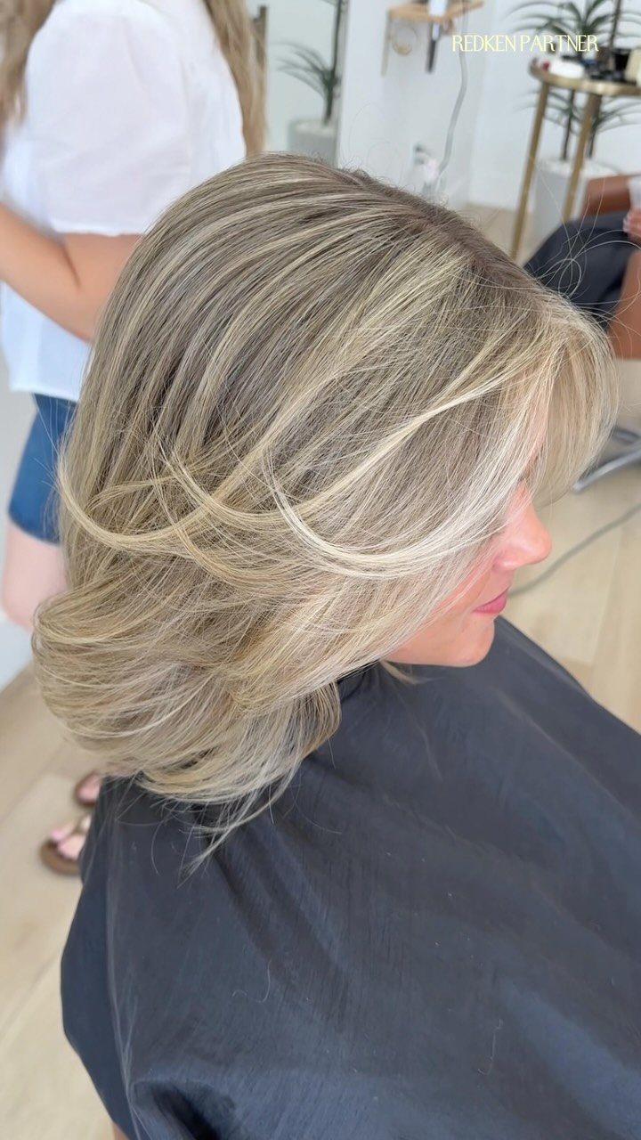 Layered soft blonde hair with muted beige highlights and darker roots
