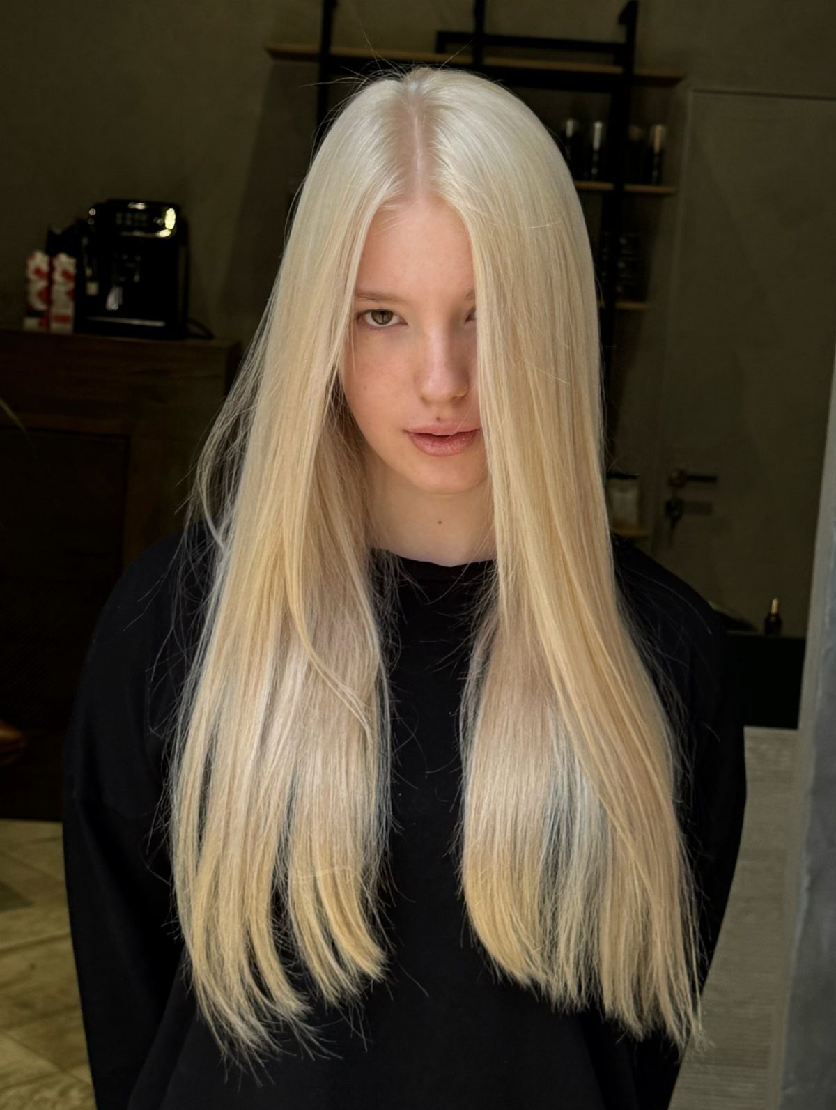 Long, uniformly pale blonde hair falls straight over a black top