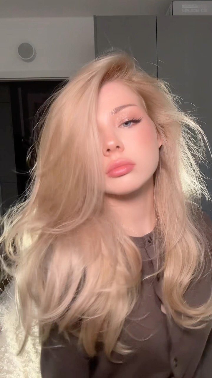 Woman with long, voluminous pale creamy blonde hair and softly curled ends