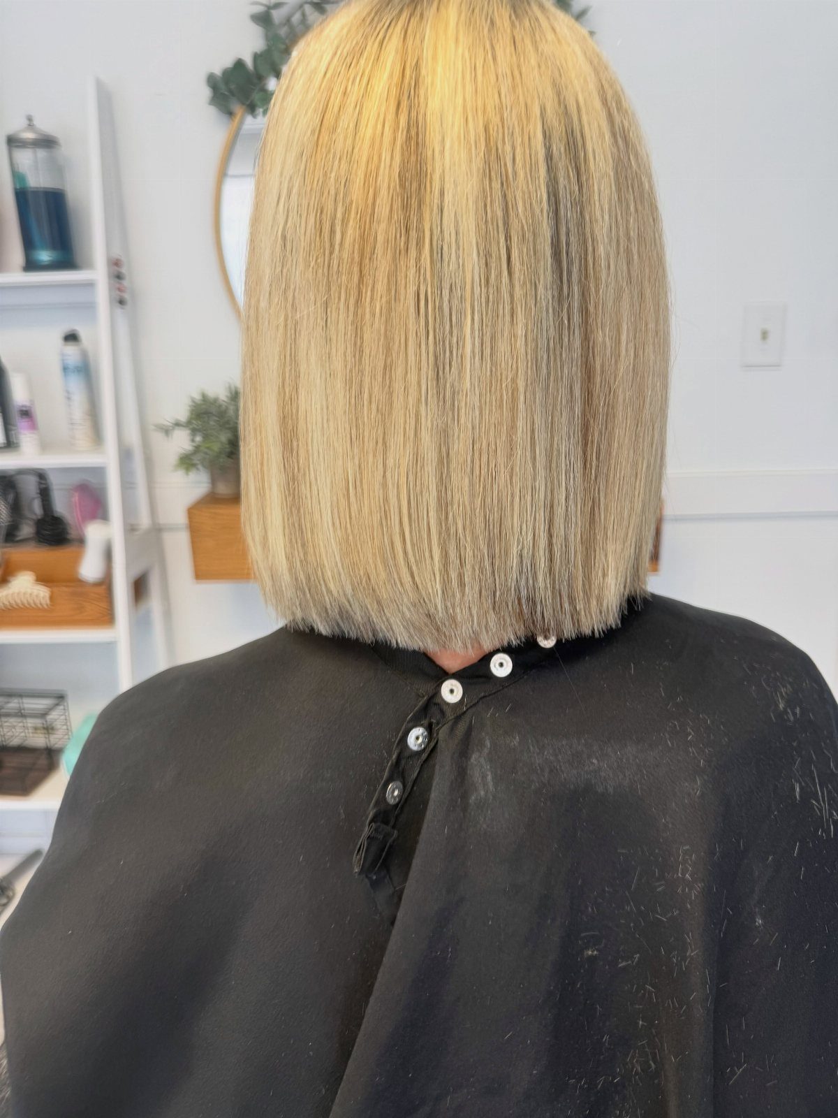 Straight blonde bob viewed from behind above a dark salon cape