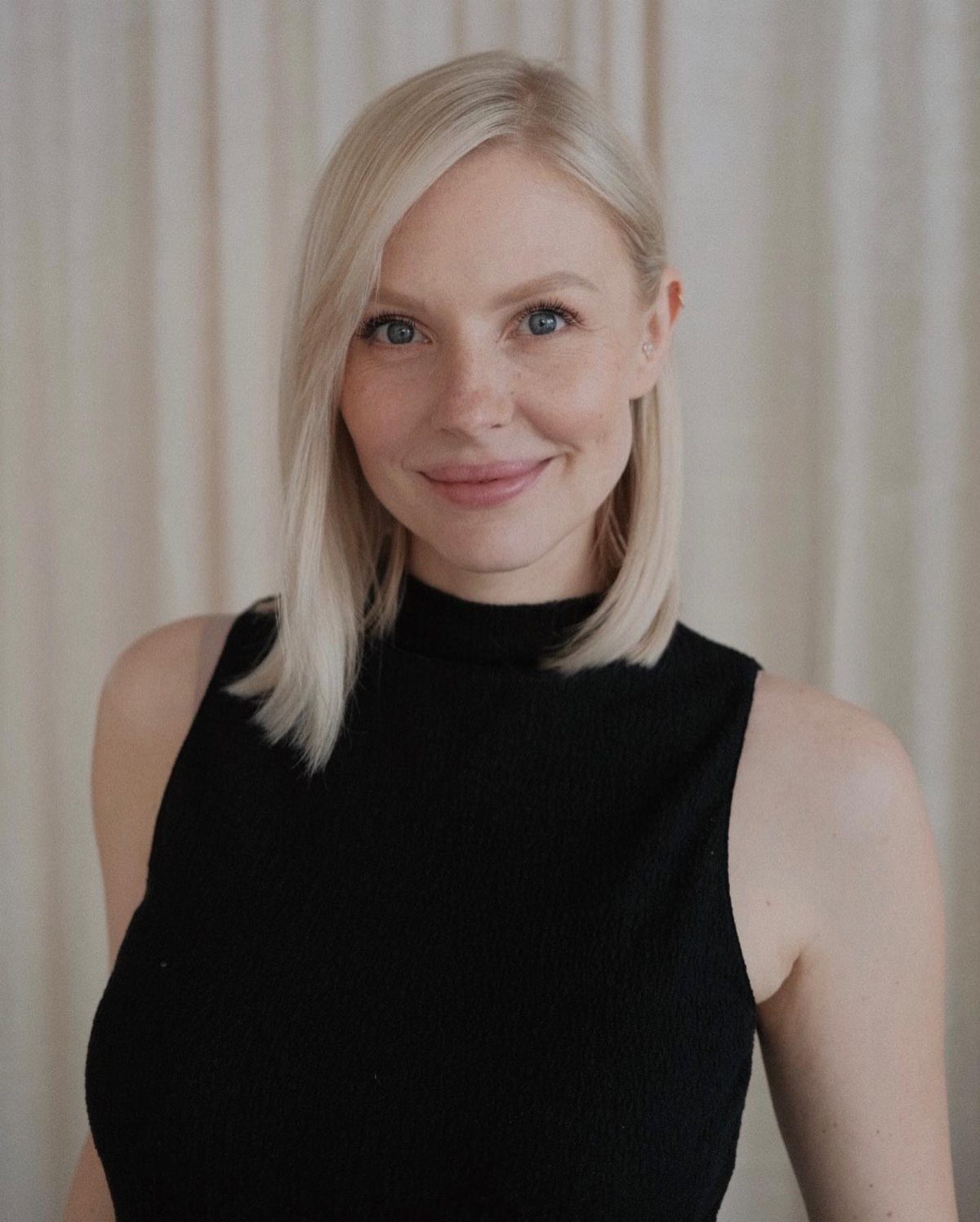 Woman with straight shoulder-length blonde hair in a simple side-parted long bob