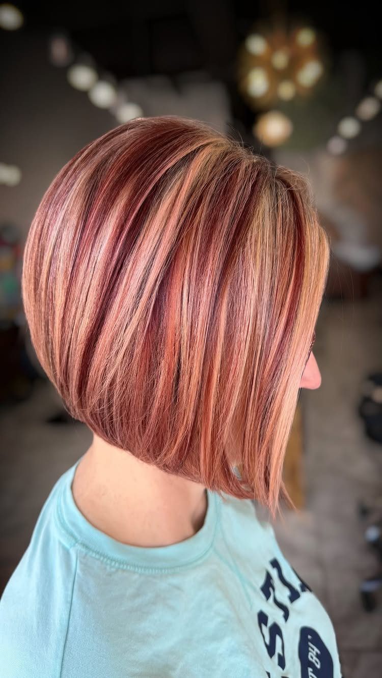 Rose-gold layered bob with a deep side part viewed from the side