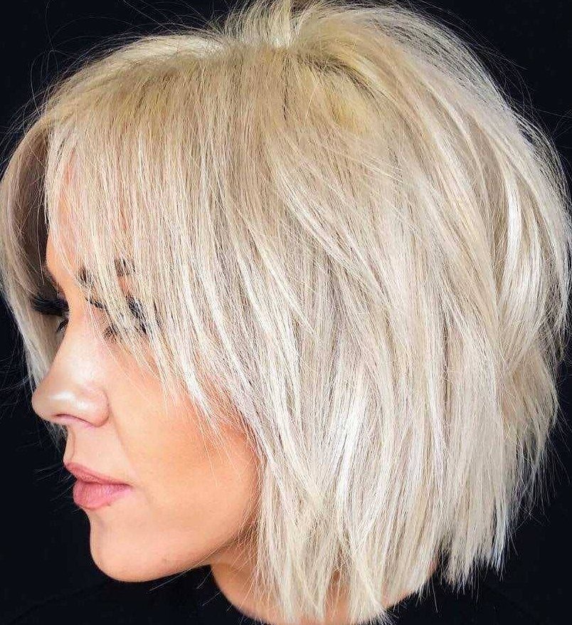 Woman with short blonde hair wearing a textured, layered shaggy bob against black